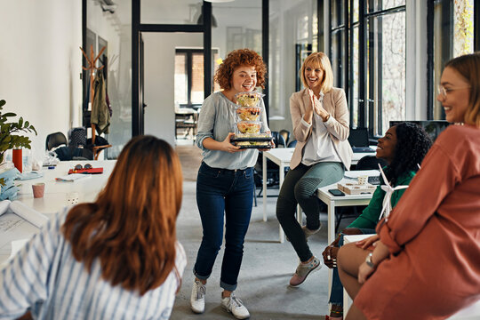 Happy businesswoman serving takeaway food to colleagues in office
