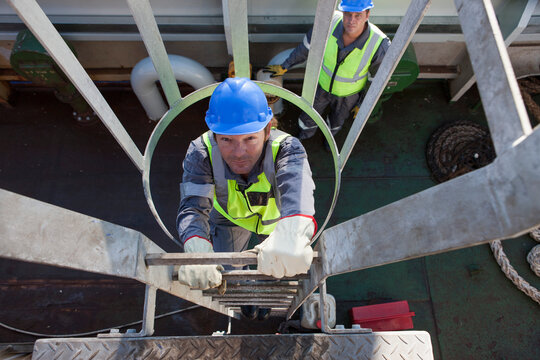Worker onboard a ship climbing up towards lookout