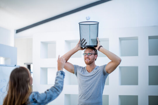 Colleagues in office throwing crumpled paper into waste paper basket