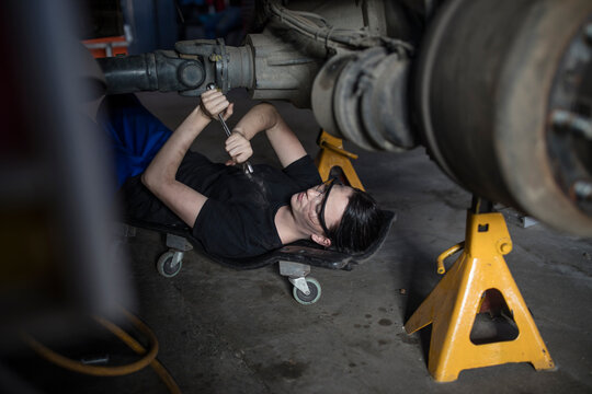 Female mechanic working at fire brigade workshop, lying on creeper