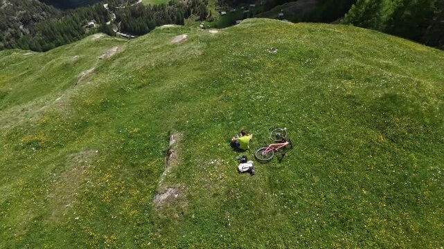 Dosso dei vetti, Chiesa in Valmalenco, Italy: Mountain Biker rests drone view from the top in the middle of the valley on a Sunny Day