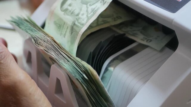An automated cash counting machine money counter quickly counts multiple Thai's banknotes with precision. The device efficiently handles paper currency for banking and financial operations.