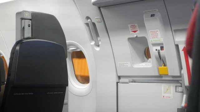 view to emergency exit door with airplane empty seat row witout any passenger while plane parking on ground ready to depart in night time fligh operating,aircraft cabin inside