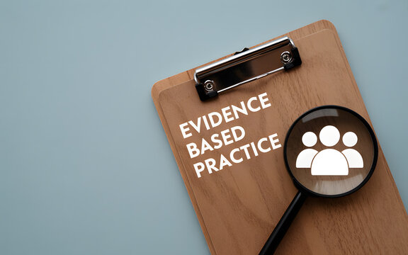 A clipboard with evidence based practice text and a magnifying glass on a blue surface