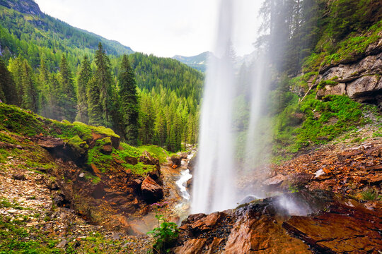 View through a waterfall into a valley with forests and mountains - johannes waterfall, Austria Alps mountain