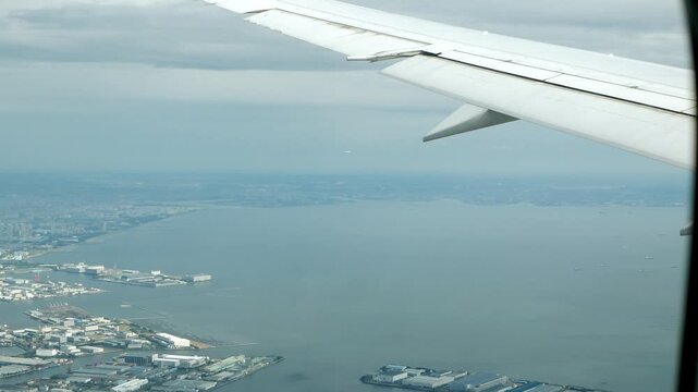 Aerial view through plane window with view of airplane wing over puffy white cloud with clear blue sky while flying, View from the window of the plane traveling by air, vacation background concept