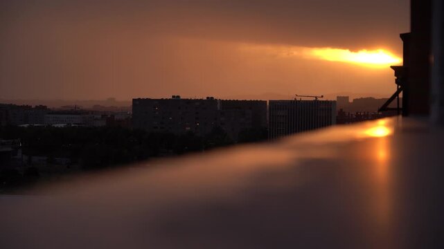 Atardecer dram&aacute;tico de intensos tonos naranjas sobre un paisaje urbano, con edificios y siluetas de la ciudad recortados contra el cielo.