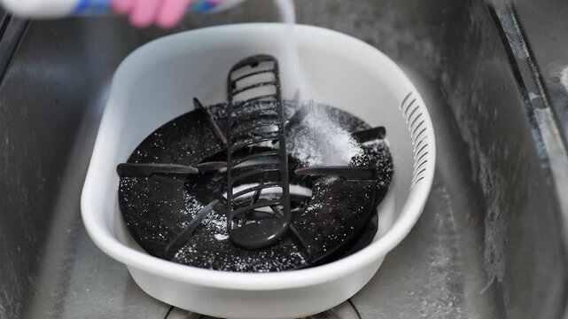 油で汚れたガスコンロの部品を取り外して洗剤を入れてお湯に浸す