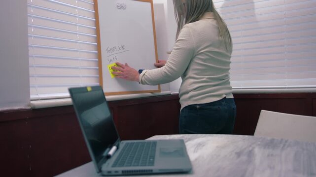 Woman in office planning workload on whiteboard
