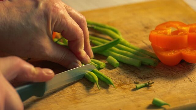 Hands chopping raw green beans