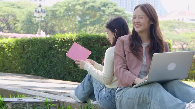 Two Asian University Students Studying Back to Back in a Sunny Park