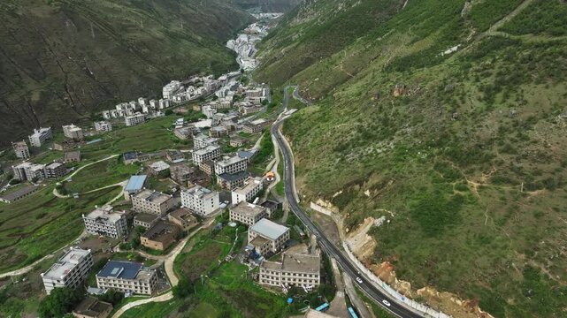 Aerial view of scattered rural settlements along winding river valley in Daocheng Yading China