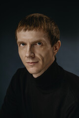 Fototapeta premium Portrait of a person with short hair and a black sweater looking at the camera indoors