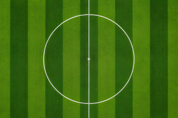 Obraz premium A clean, flat top-down graphic illustration or photography of a bright green soccer field showing the center line and striped turf patterns.
