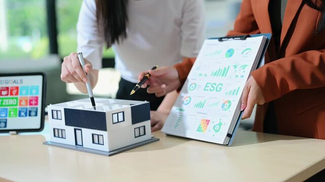 Modern office meeting of architects, designers, and developers creating innovative, sustainable housing projects using building models and digital tools.