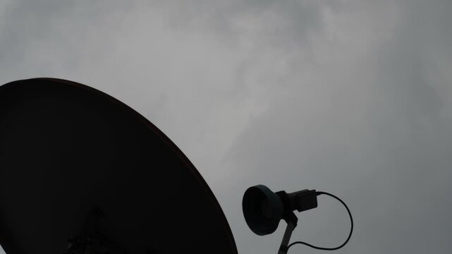 Satellite Dish Silhouette Against Moving Clouds Timelapse