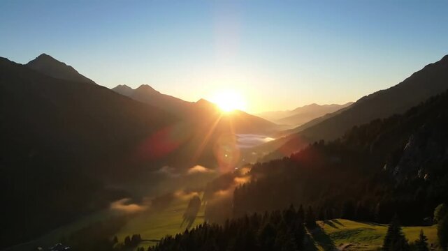 Serene mountain valley with fog at dawn and colorful sky