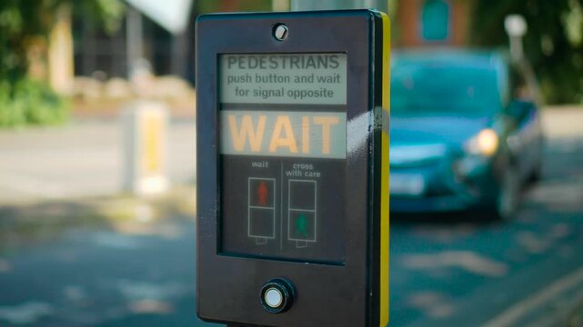 Crosswalk control button activation on pedestrian traffic signal beside city street. Female hand touching crossing panel while waiting for safe road crossing permission. Urban mobility and public