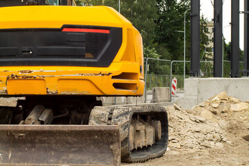 Fototapeta premium Yellow excavator in the city construction business asphalt road rebuilding closeup photo background