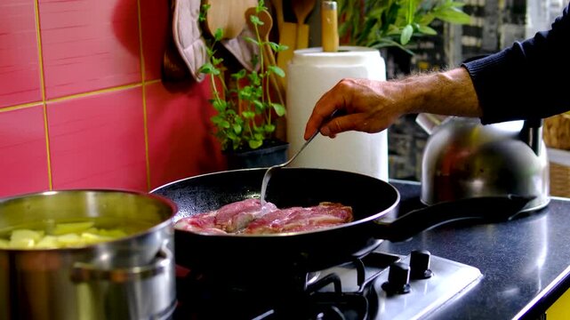 video set of a man cooking steaks in a frying pan, Chef cook sets stewpan meat steak on frying pan. Making delicious dishes process. Restaurant with gourmet cuisine. Public catering concept.