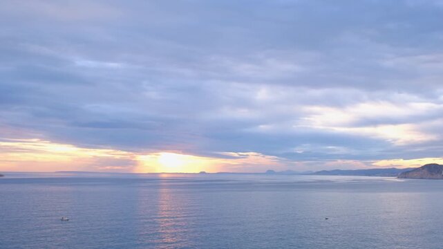 Sunset view over Cala Tio Ximo and Benidorm island. Tranquil winter sea, soft sunset glow, peaceful view of small island near Benidorm. Quiet natural beauty, no people, only sea and sky.