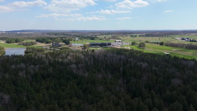 Dense forest adjacent to TPC Toronto golf course, highlighting lush greens and open skies.