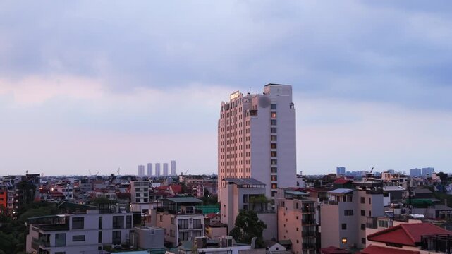Slow drone push toward Hanoi skyline at dusk with stormy clouds, Vietnam city and urban mood.