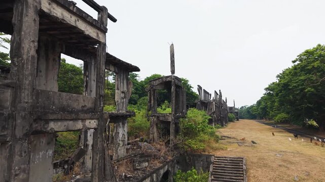 Drone rises and pushes along endless row of gutted WWII barracks facades on Corregidor Island, pacific history landmark.