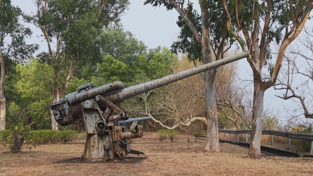 Drone pulls back from rusted WWII anti-aircraft artillery cannon on Corregidor island, military heritage view.