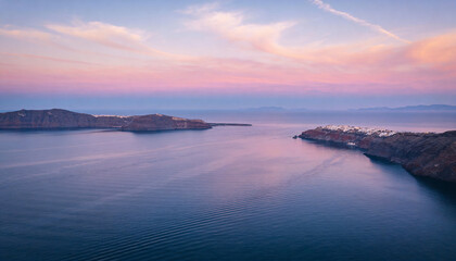 Obraz premium Showing open sea reflecting pastel sky from drone, with ripples, peninsula and white cliff village
