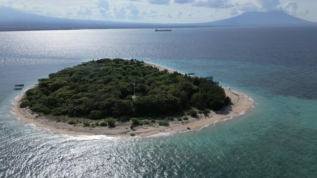 Aerial Overview of Tabuhan Island with coast of East Java, volcano and passing ship in the background