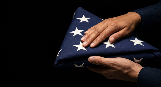 Hands holding a folded American flag with respect