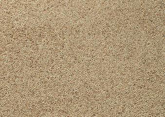 Fototapeta premium Dry amaranth grains in big pile on table close up. Large amount of yellow amaranth grains