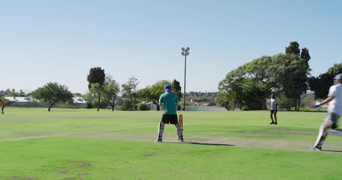 Bowler delivering ball, batsman hitting before fielder breaking stumps celebrating on ground