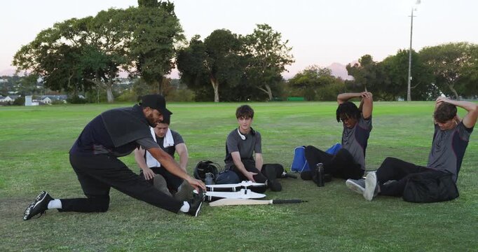 Diverse teammates warming up following coach demo hamstring then triceps stretches on field