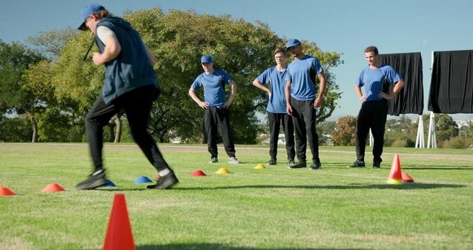 Training diverse male teammates in blue uniforms navigating cones for agility on field