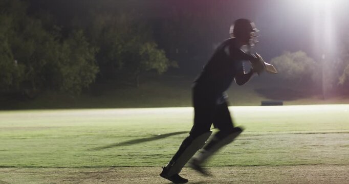 Diverse partners under floodlights, batsman swinging bat to score walking off, outfielder watching