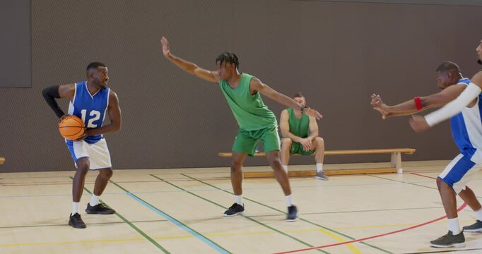 Dribbling basketball, scanning court, male guard initiating alley-oop finish to score at gym