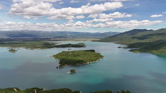 Scenic aerial drone footage of the unique Slano Lake near Niksic, Montenegro. The video captures the beautiful blue water, distinctive green islands, and the rugged Balkan landscape under bright dayli