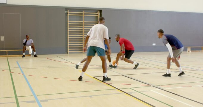 African american player dribbling basketball with crossover evading block on sideline