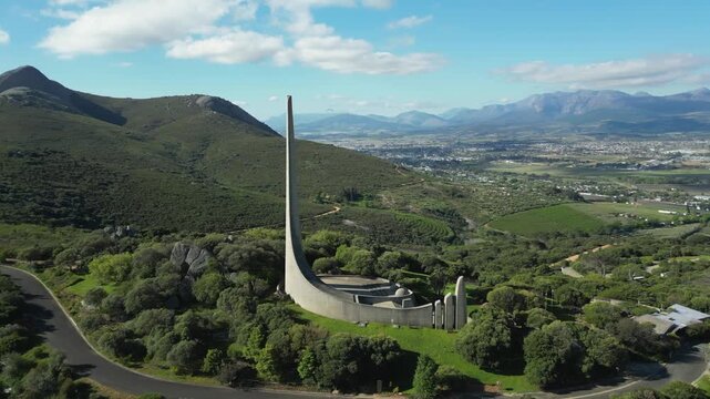 Aerial orbit around Afrikaans Language Monument on green hill overlooking Paarl town