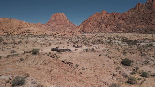 Aerial descending view of himba village near spitzkoppe mountain in namib desert, namibia, during a sunny day in africa
