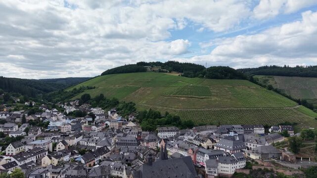 Drone panorama of Saarburg historic old town in Saarland, Germany. Traditional architecture, St. Laurentius Church and surrounding vineyards create a picturesque landscape beneath dramatic summer clou