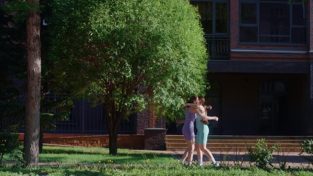 Two happy twin sisters finishing their run, giving a high five and hugging each other in a park