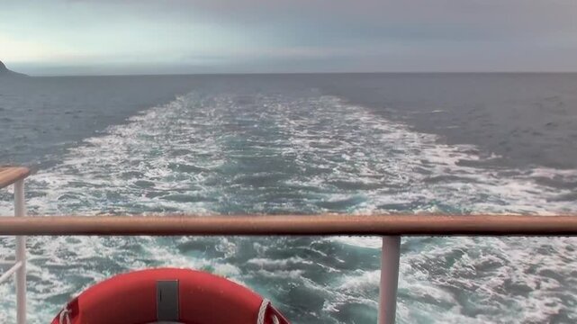 A captivating journey across the Arctic Ocean unfolds. The ship carves a brilliant, foamy trail on the expansive northern waters, stretching toward the distant horizon under a serene sky.