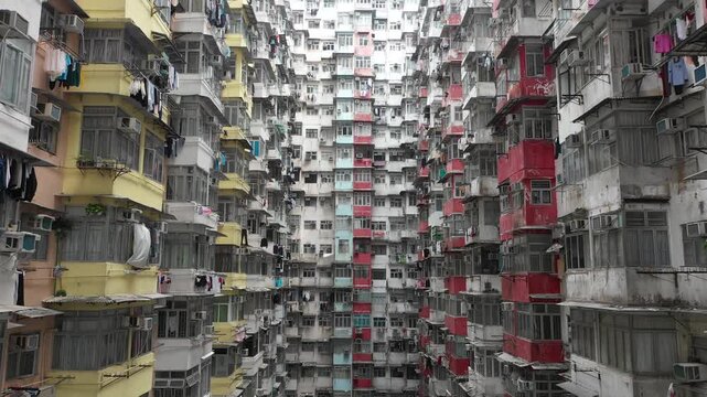 Upwards tilting drone shot of people drying laundry in dense residential apartment tower in Quarry Bay district of Hong Kong
