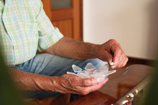 Senior man taking daily medication from pill organizer