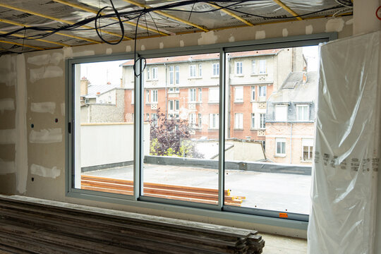 Espace en r&eacute;novation montrant des travaux sur les fen&ecirc;tres, les murs et la toiture, illustrant un chantier de transformation et de restauration d&rsquo;un b&acirc;timent.