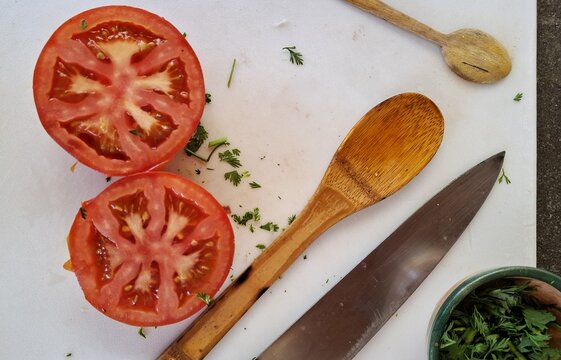 Tomates, persil et ustensiles de cuisine sur une planche de d&eacute;coupe. Pr&eacute;paration d'un plat m&eacute;diterran&eacute;en frais.