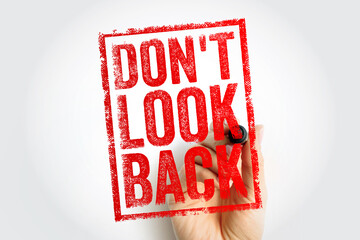 Obraz premium DONT LOOK BACK red stamp text held by a hand. Inspirational quote encouraging focus on the future and moving forward, skipping the past for personal growth and mental health motivation